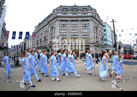London, UK. 20th October 2015. Gift of Life organ donor awareness demonstration at Oxford Circus, London. London commuters were given pause to think as 'patients' looking for an organ donor hit the rush hour at Oxford Circus. The 21 people dressed in surgical gowns represent the number of people each week (3 every day) who die in need of a transplant. Credit:  Paul Brown/Alamy Live News Stock Photo