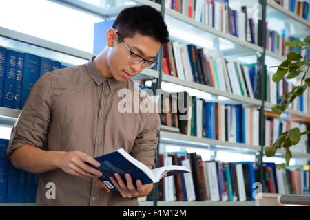 Portrait of a young asian man reading book in library Stock Photo