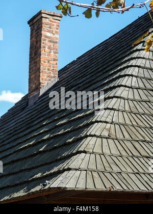 Closeup of wooden shingle roof with brick chimney Stock Photo