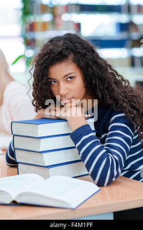 Portrait of a serious afro american woman sitting at the table with books in classroom Stock Photo