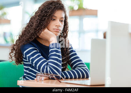 Portrait of a serious female student watching something on laptop computer Stock Photo