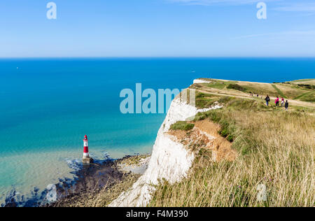 Walkers on the clifftop path overlooking the lighthouse at Beachy Head, near Eastbourne, East Sussex, England, UK Stock Photo