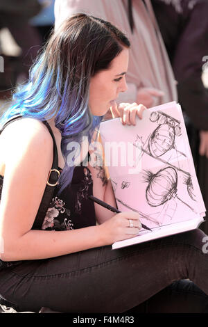 Young woman sketching Chinese lanterns outdoors in artist's sketchbook Stock Photo