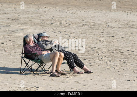 An elderly couple enjoying the sun on a empty British beach, England, UK Stock Photo