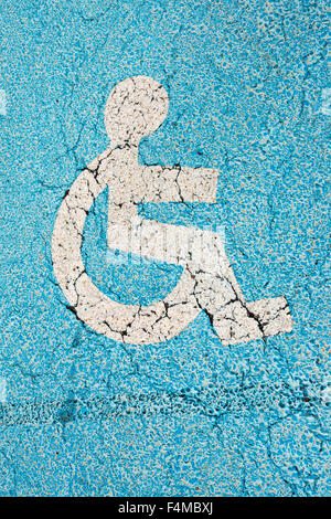 A photo of a blue disabled parking sign painted on the ground in a car park Stock Photo