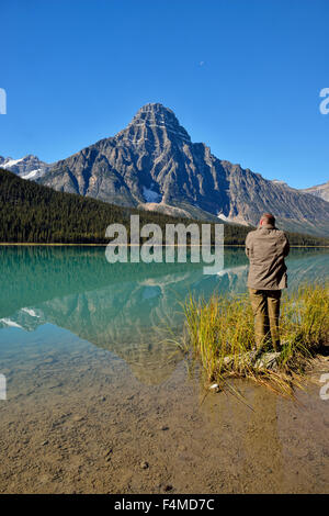 Photographer on the shore of Waterfowl Lake with Mt. Chephren, Banff National Park, Alberta, Canada Stock Photo