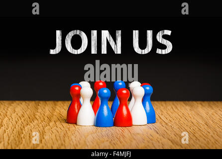Concept for join us, join our team with white chalk text. Red white blue pawn figures and black background on oak. Stock Photo