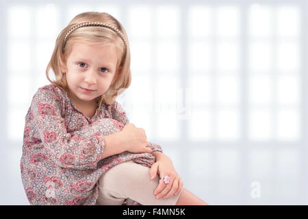 Cute little girl sitting in front of windows Stock Photo