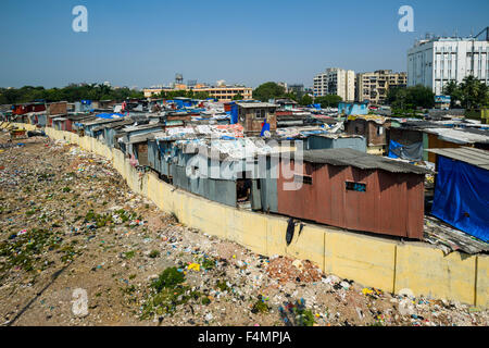 A slum area behind a wall and with new buildings in the distance Stock Photo