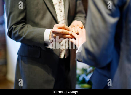 Man putting on ring on partner Stock Photo