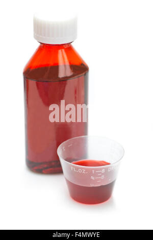 Red cough and cold liquid cold medicine in measuring cup on white. Stock Photo