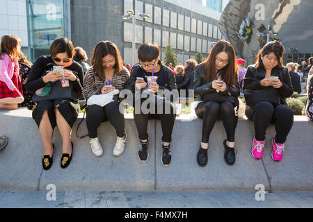 Teenagers using their smart phones in Birmingham city centre, UK
