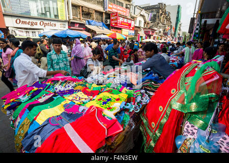 Salesmen are offering cloths for sale in a crowded street with shops at Mangaldas Market Stock Photo