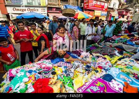 Salesmen are offering cloths for sale in a crowded street with shops at Mangaldas Market Stock Photo