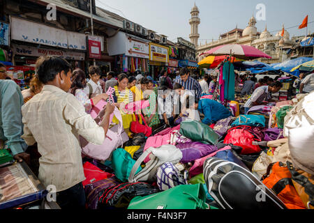 Salesmen are offering bags for sale in a crowded street with shops at Mangaldas Market Stock Photo