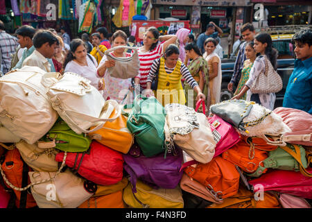 Salesmen are offering bags for sale in a crowded street with shops at Mangaldas Market Stock Photo