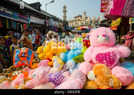 Salesmen are offering plush toys for sale in a crowded street with shops at Mangaldas Market Stock Photo