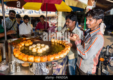 Salesmen are offering snacks for sale in a crowded street with shops at Mangaldas Market Stock Photo