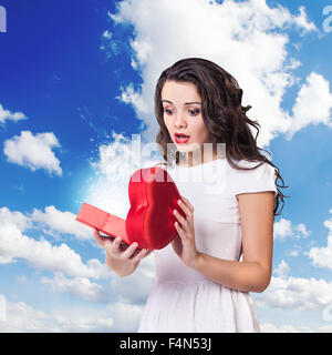 Young surprised woman holds open heart box Stock Photo