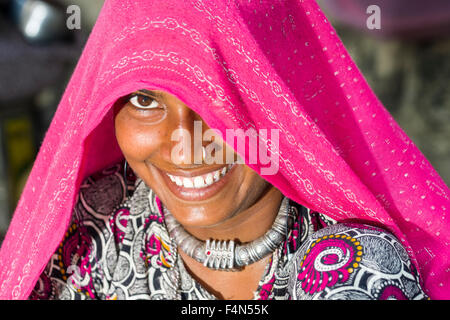 A beautiful young woman covered in a pink veil is smiling brightly Stock Photo