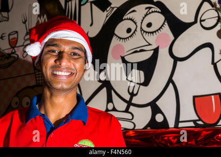 A waiter is wearing a Santa Claus hat at Christmas in a tourist restaurant in the suburb Colaba Stock Photo