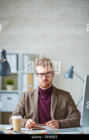 Young businessman looking at camera with suspicious expression Stock Photo