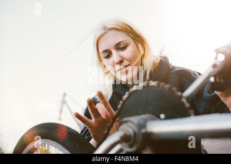Young woman repairing BMX bicycle Stock Photo