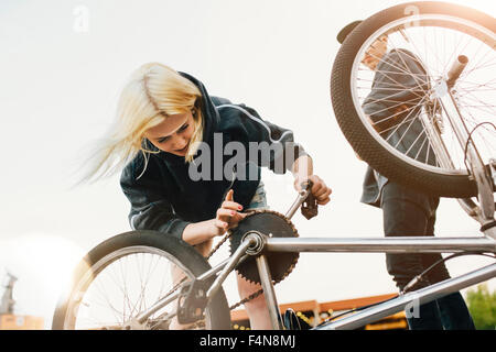 Young woman repairing BMX bicycle Stock Photo