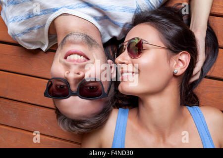 Happy young couple lying head to head on a wooden floor