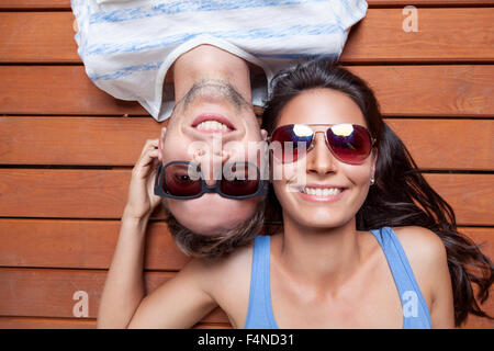 Happy young couple lying head to head on a wooden floor
