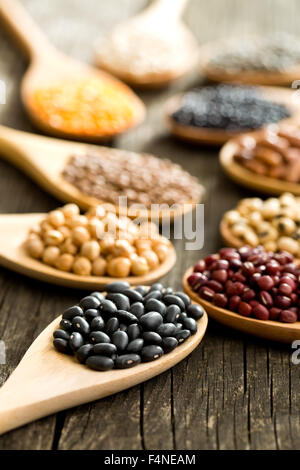 various dried legumes in wooden spoons on old table Stock Photo