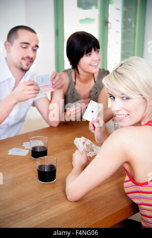 Young woman showing ace of spades while her friends playing cards Stock Photo