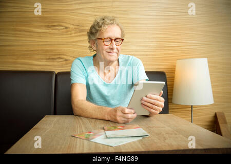 Smiling senior man in a cafe using digital tablet Stock Photo