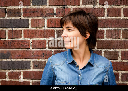 Woman leaning against a brick wall Stock Photo