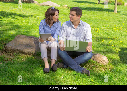 Students with laptop sitting on stone Stock Photo