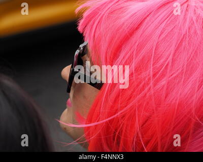 profile view of female with bright pink dyed hair matching pink lipstick and black spectacles Stock Photo
