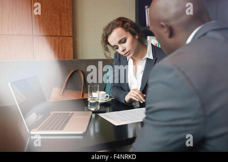 Serious business people working together in a cafe and reading some contract documents. Businessman and businesswoman discussing Stock Photo