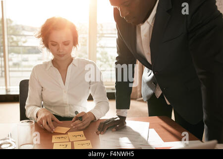 Shot of young business colleagues in conference room discussing working plan. Businesswoman sitting with adhesive notes with man Stock Photo