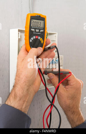 Hand of an electrician with multimeter probe at an electrical switchgear Stock Photo
