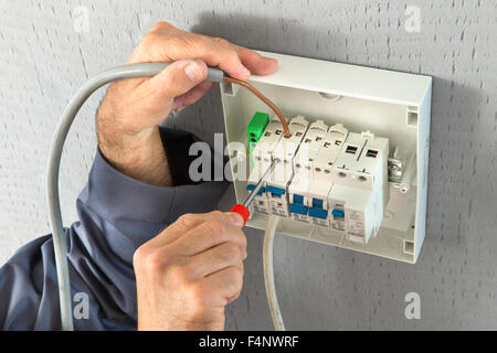 electrician builder engineer screwing equipment in fuse box Stock Photo