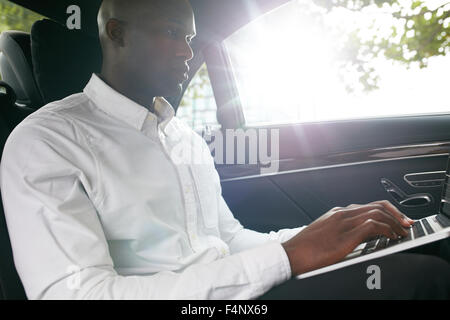 Businessman traveling to office in the luxury car on the back seat and working on the laptop. Stock Photo