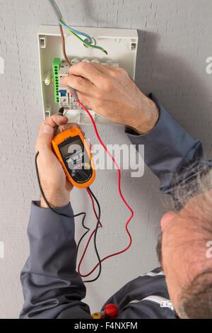 Hand of an electrician with multimeter probe at an electrical switchgear Stock Photo