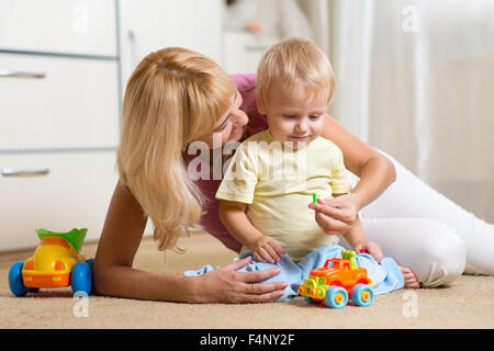 kid boy and his mother repair toy car at home Stock Photo