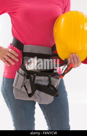 Close up of woman builder with hardhat in hands and tools belt Stock Photo