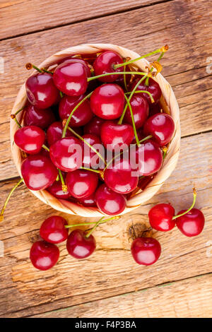 Fresh cherries in basket on wooden table. Stock Photo