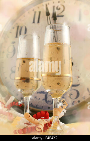 Champagne in glasses with ribbons with new years countdown vintage clock in the background Stock Photo