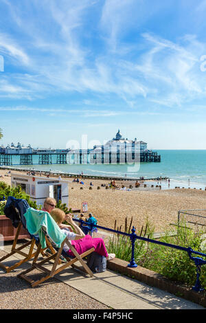 Two elderly women sitting on the promenade with the beach and pier behind, Grand Parade, Eastbourne, East Sussex, England, UK Stock Photo