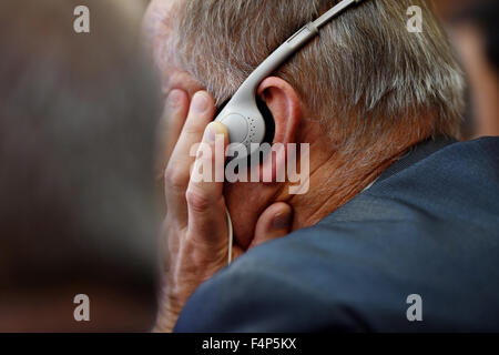 Unrecognizable man using in ear headphones for translation during event Stock Photo
