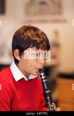 Young boy playing the clarinet - shallow depth of field - warm tones. Portrait layout. Copy space top. Stock Photo