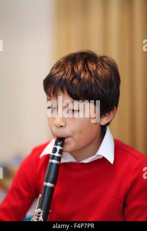 Young boy playing the clarinet - shallow depth of field - warm tones. Portrait layout. Copy space top. Stock Photo